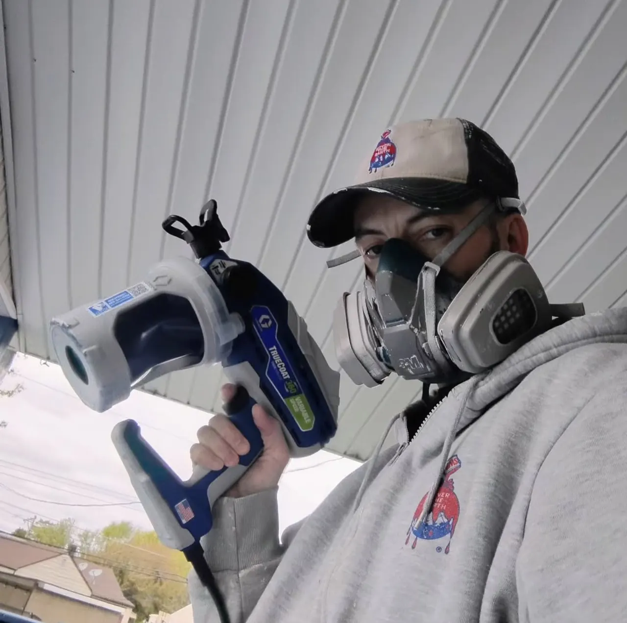 Keith Torres in a respirator holding a paint sprayer